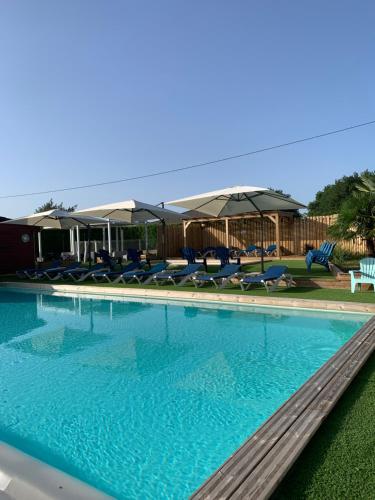 une grande piscine avec chaises et parasols dans l'établissement OPHEA 2 Personnes, à Limeuil