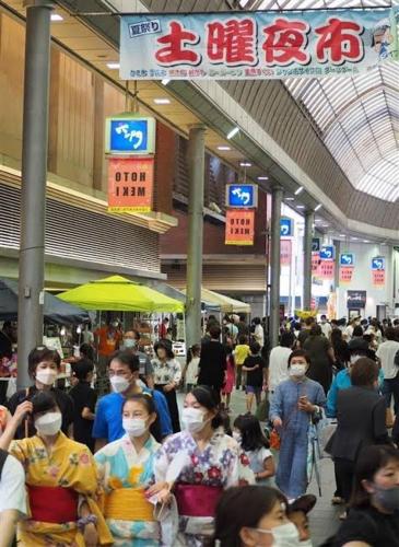 a group of people wearing face masks in a mall at Base605 in Kurume
