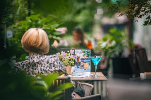 a woman sitting at a table with a glass at Boutique Hotel Townhouse 27 in Belgrade