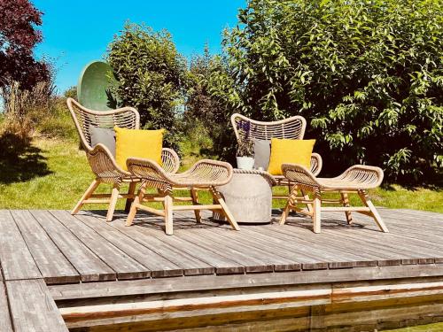 three wicker chairs with yellow pillows sitting on a wooden deck at Sylter Seestern App Hortensie in Morsum