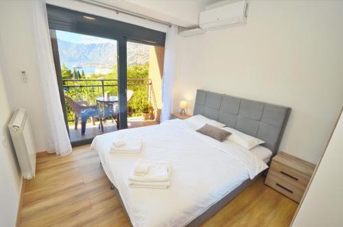 a bedroom with a large white bed and a balcony at Radgost Kotor Apartments in Kotor