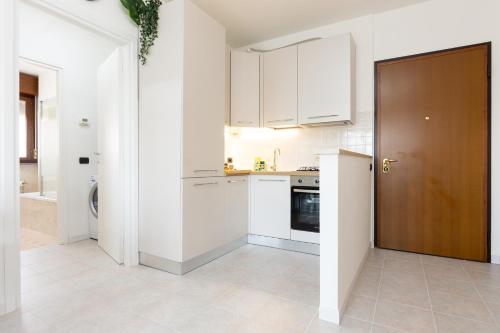 a kitchen with white cabinets and a brown door at GuestHost - Casa Le Palme in Pioltello