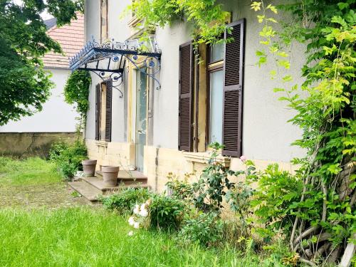 a house with a porch and some grass and flowers at Le Jardin d'Eden in Ay-sur-Moselle