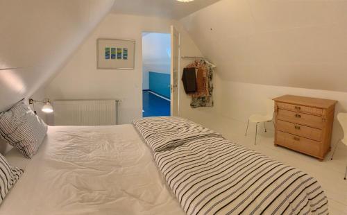 a bedroom with a large white bed and a dresser at Mindedalen - Idyl tæt på alt og helt i fred in Billum
