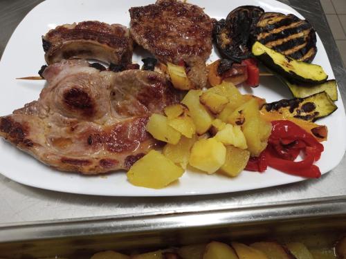 a white plate of food with meat and vegetables at La Caigola in Ala