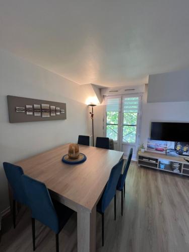 une salle à manger avec une table en bois et des chaises bleues dans l'établissement Appartement Cosy Disneyland, à Magny-le-Hongre
