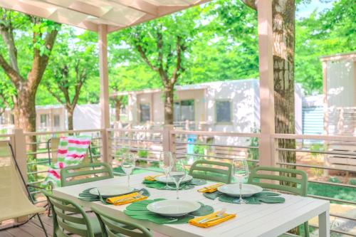 a white table with green napkins and glasses on a porch at Camping Village Riva Blu in Padenghe sul Garda