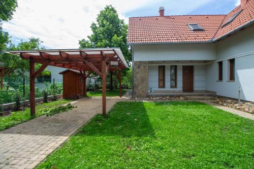 a garden with a wooden pergola next to a house at Levendula Villa in Balatonőszöd