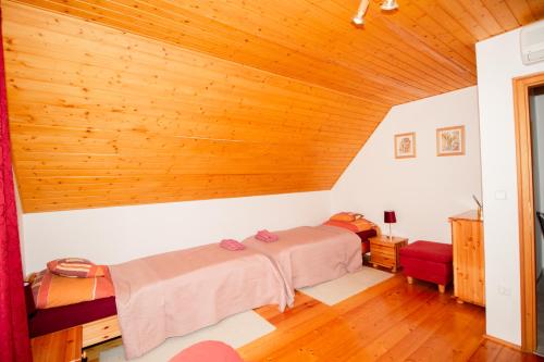 a bedroom with two beds and a wooden ceiling at Levendula Villa in Balatonőszöd