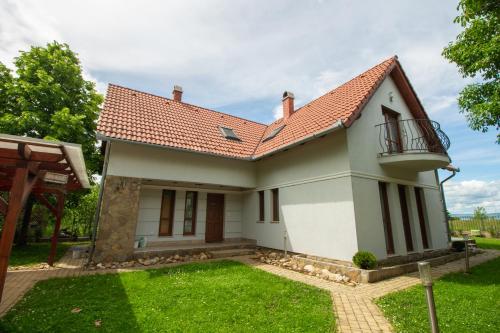 a small white house with a balcony and grass at Levendula Villa in Balatonőszöd