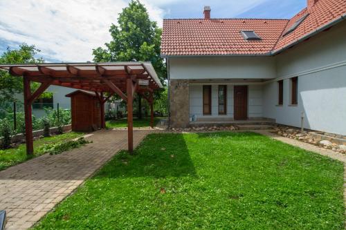 a house with a wooden pergola in the yard at Levendula Villa in Balatonőszöd