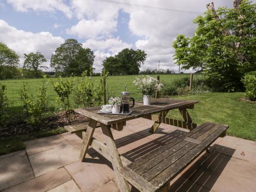 a wooden picnic table in a garden with a field at The Coach House in Ludlow