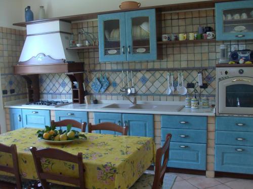 a kitchen with blue cabinets and a table with a bowl of fruit at Il Melicucco in Furci Siculo