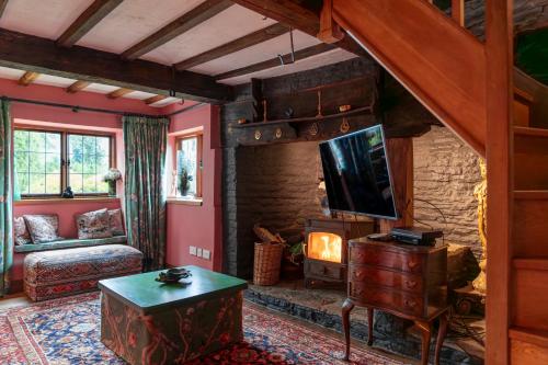 a living room with a fireplace and a tv at Llethrau Forest & Nature Retreats in Knighton