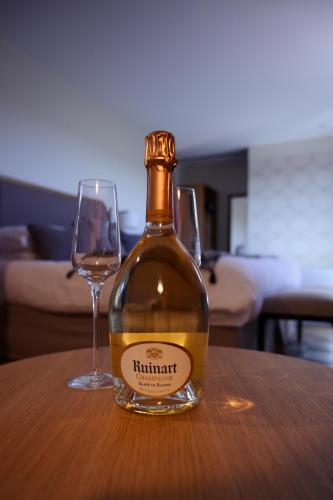 a bottle of wine sitting on a table with two glasses at Hôtel Boutique Cézanne centre Aix-en-Provence in Aix-en-Provence
