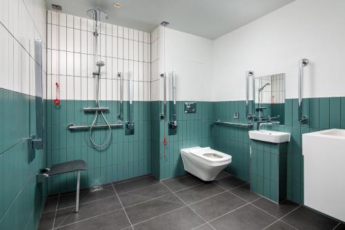 a bathroom with green walls and a toilet and a sink at Southgate Hotel London in East Barnet