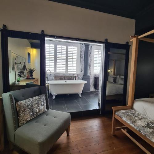 a bathroom with a tub and a bedroom with a bed at What’s behind the green door! in Cape Town