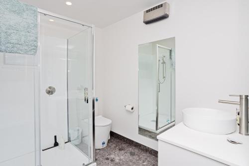 a white bathroom with a shower and a toilet at Southern Breeze - Colac Bay Beach House in Riverton