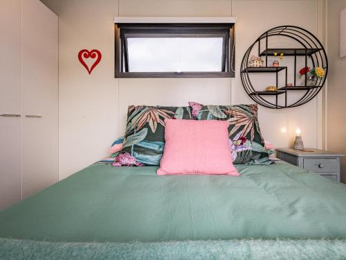 a bedroom with a green bed with a pink pillow at Whare Awa - River House in the Rangitīkei in Hunterville