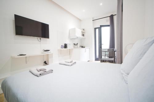 - une chambre blanche avec un lit et une télévision murale dans l'établissement LOVELY PARISIAN APARTMENT, à Paris
