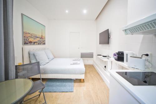 Cette petite chambre blanche dispose d'un canapé et d'une table. dans l'établissement LOVELY PARISIAN APARTMENT, à Paris