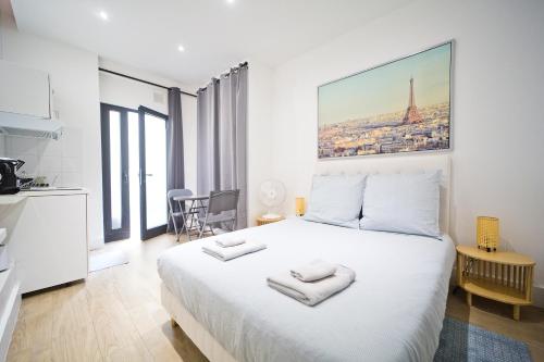 - une chambre blanche avec un grand lit et des serviettes dans l'établissement LOVELY PARISIAN APARTMENT, à Paris