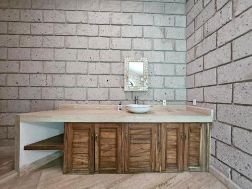 Un baño con lavabo y pared de ladrillo. en Finca Agua Salada, en Xochitepec