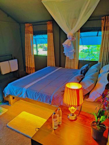 a bedroom with a bed and a table with a lamp at Harmony Haven, Udawalawe, Sri Lanka in Udawalawe