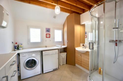 Un baño con lavadora y lavabo. en Villa Anne - 500m de la mer - SPA, en Moëlan-sur-Mer