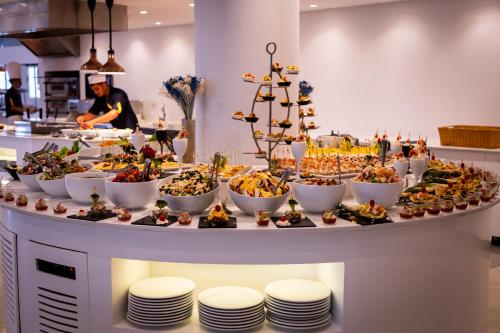 a buffet of food on a table with plates at Royal Tulip Taj Sultan in Hammamet