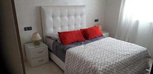 a bedroom with a bed with two red pillows at Appartement Agadir Awrir in Agadir