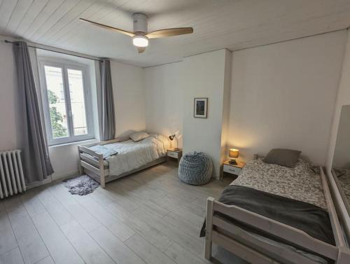 une chambre avec deux lits et un ventilateur de plafond dans l'établissement à 5mn de la réserve Africaine, charmante maison de village avec patio, à Sigean