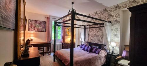 - une chambre avec un lit à baldaquin et des oreillers violets dans l'établissement Bergerac Chambre d'hôte oiseaux de paradis, à Bergerac