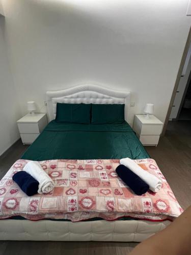 a bedroom with a bed with a green comforter and two tables at FronteMare Luxury in Montesilvano