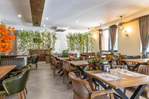 a restaurant with wooden tables and chairs and plants at Hotel Domenic FREE PARKING in Plovdiv