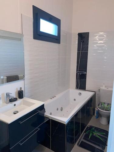 une salle de bain avec une baignoire, un lavabo et des toilettes dans l'établissement MH Logement - Chaleureuse maison scandinave, à Nîmes
