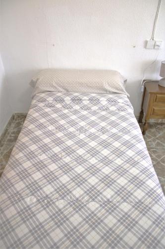 a bed with a checkered blanket on top of it at Vacansis Habitaciones Privada en una Villa a un paso del Mar en Cullera in Cullera