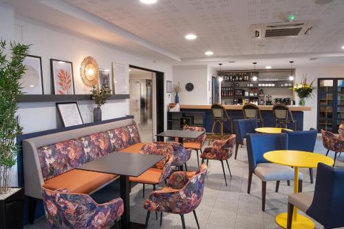 a restaurant with tables and chairs and a bar at Domitys Les Sources de Gascogne in Dax