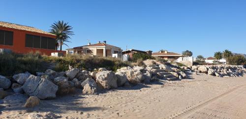 a row of rocks on a beach next to a house at Vacansis Habitaciones Privada en una Villa a un paso del Mar en Cullera in Cullera