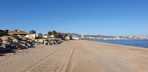 a sandy beach with rocks and the ocean at Vacansis Habitaciones Privada en una Villa a un paso del Mar en Cullera in Cullera