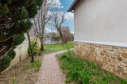 a brick path next to a stone wall at Maison spacieuse 3 chambres à 5 min de la gare in Juvisy-sur-Orge