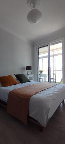 une chambre avec un grand lit avec une grande fenêtre dans l'établissement Appartement avec vue près des plages, à Sète