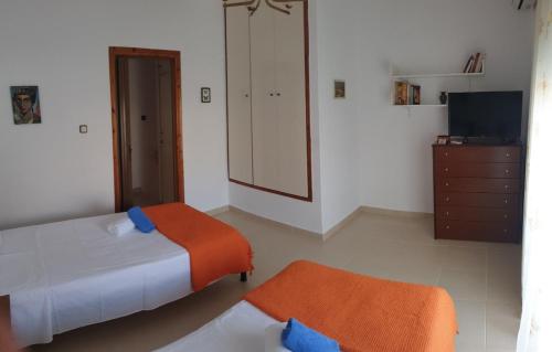 a bedroom with two beds and a dresser and a television at Lovely maison house 50m from the beach at Nea Flogita in Flogita