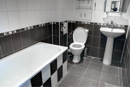 a bathroom with a tub and a toilet and a sink at Neon Guest Rooms in Shumen