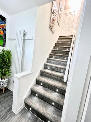 a stairway leading up to a white door with a gray stair runner at Home away from home in Bury
