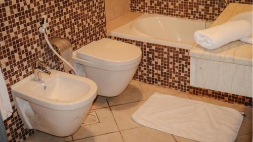 a bathroom with a toilet and a sink and a tub at Sandy palace Hotel in Amman