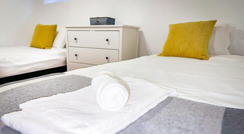 a bed with a white towel on it with a dresser at T2 Apartment -Cascais center - 100m from beach in Cascais