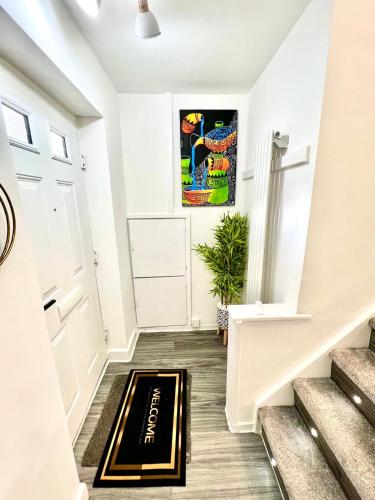 a hallway with stairs with a welcome mat on the floor at Home away from home in Bury