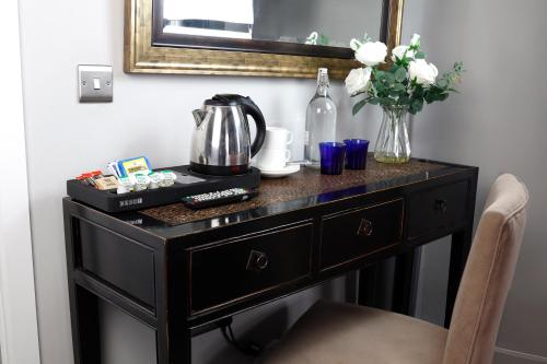 a black dresser with a vase of flowers and a mirror at Granary Villa in Kidderminster