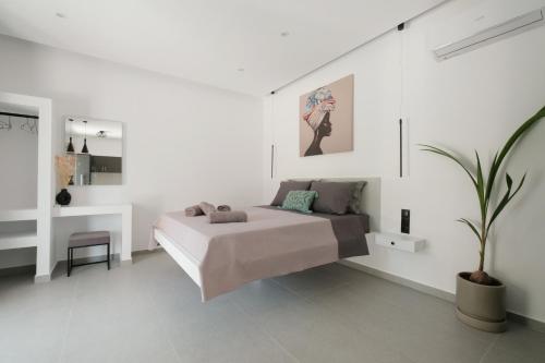 a white bedroom with a bed and a potted plant at Mouzakitis Studio 1 in Arillas